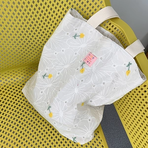 Close-up of white daisy embroidery and pink handmade label on the canvas tote bag