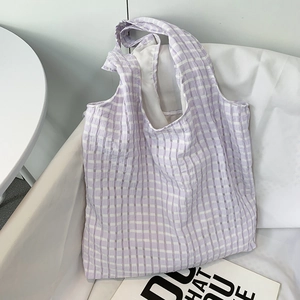 Detail of lavender and white checkered canvas tote bag on a white sofa setting