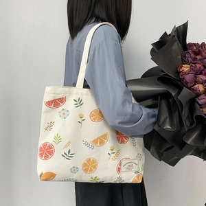 Detail of canvas tote bag with orange prints and decorative text patch on shoulder
