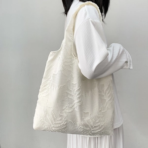 Detailed view of white tote bag with 3D leaf texture on soft fabric for women