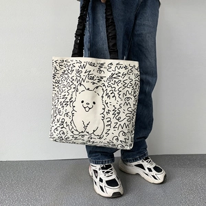 Detail of canvas tote bag with black doodle handle and cute puppy cartoon illustration