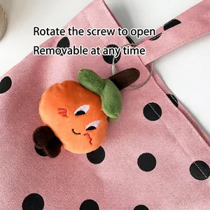 Pink polka dot canvas tote bag with a cute orange fruit plush keychain attached