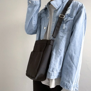 Detail of adjustable strap and front pocket on a minimalist black canvas crossbody bag