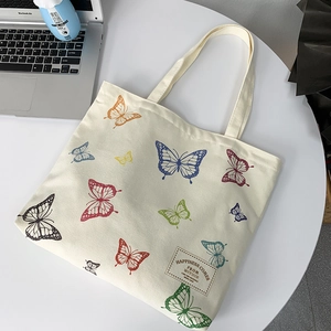 Detail of canvas tote bag featuring colorful butterfly patterns and woven label branding