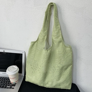 Detailed view of light green tote bag with 3D leaf texture on a textured wall background