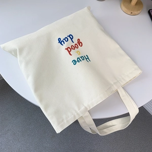 Close-up of white canvas tote bag with colorful Have a good day art lettering design