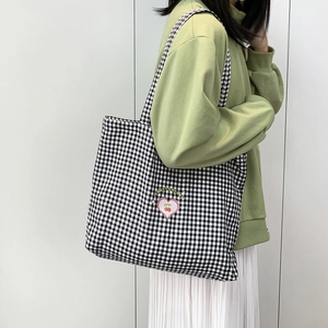 Détail du sac fourre-tout à carreaux noir et blanc avec motif cerise sur un modèle
