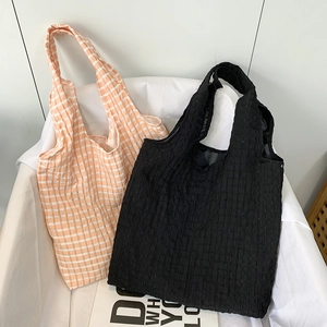 Detail of orange gingham and black textured bubble fabric tote bags with wide straps