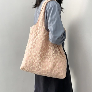 Detail of floral embroidery on light pink tote bag showing daisy patterns and fabric texture
