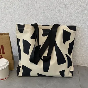 Detail view of large canvas tote bag with black geometric patterns and student slogan