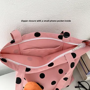 Close-up of pink polka dot canvas tote showing zipper closure and internal phone pocket