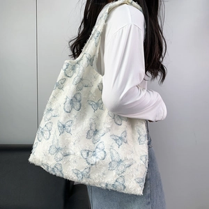 Detail of blue butterfly jacquard fabric and fringe edges on a canvas tote bag