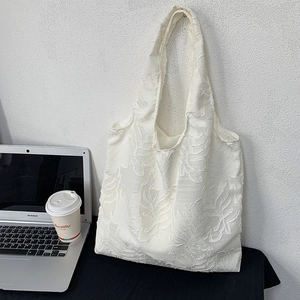 Detailed texture of white leaf patterns on a stylish commute tote bag with a laptop