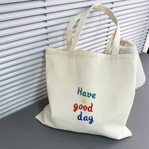 Detail of minimalist cream canvas tote bag with Have a good day artistic text print
