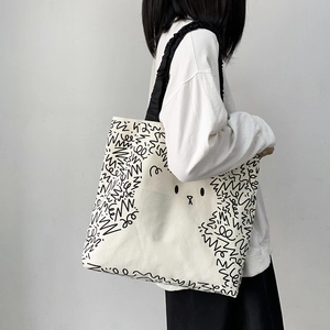 Canvas tote bag detail showing frilled black straps and cute bear doodle artwork