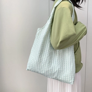 Light green striped canvas tote bag with pleated texture shown from a side view