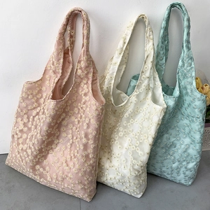 Close-up of floral embroidery on light organza tote bags in pink and green