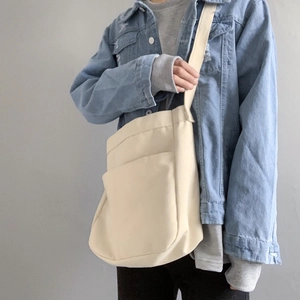 Detail of cream canvas crossbody bag showing adjustable wide strap and front pocket