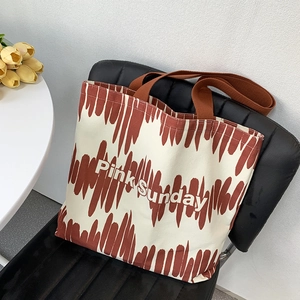 Dettaglio della borsa tote Pink Sunday in tela con manici marroni su sedia di pelle nera