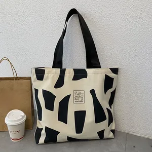 Detailed close-up of a cream canvas tote bag featuring an artistic rabbit and text pattern