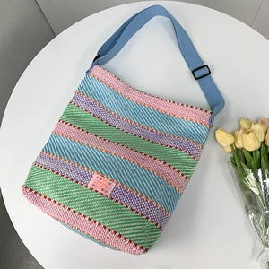 Detail einer bunten gewebten Tasche mit handgefertigtem Label und blauem Gurt