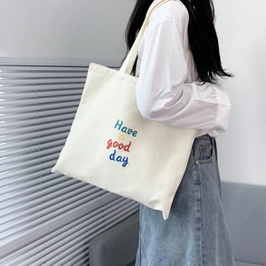 Close-up of white canvas tote bag with Have a good day print and long shoulder straps