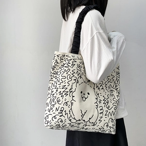 Detail of canvas tote bag with black cartoon dog print and ruffled shoulder strap