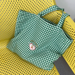Détail du sac en toile à damier vert et blanc avec imprimés cerises et cœurs doux