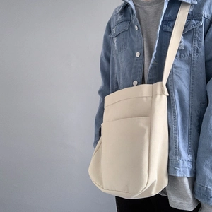 Side view of cream canvas crossbody bag showing large capacity and wide shoulder strap
