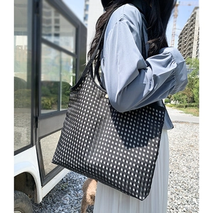 Detail of minimalist black and white checkered tote bag with golden button and mesh texture