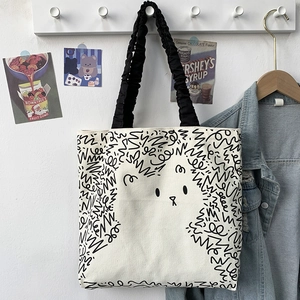 Cute cartoon puppy canvas tote bag with black pleated handles hanging on a white wall