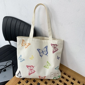 Detailed close-up of butterfly print and woven label on beige canvas tote bag