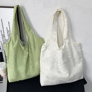 Detail of light green and off-white tote bags featuring a 3D leaf texture jacquard fabric