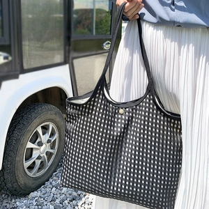 Close-up of black and white checkered canvas tote bag with a secure magnetic metal buckle