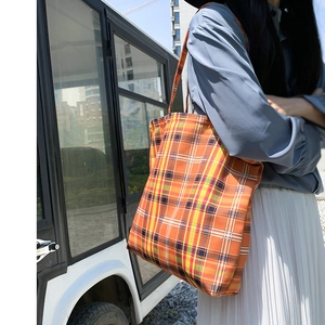 Détail du grand sac cabas à carreaux orange et jaune lors d'une utilisation