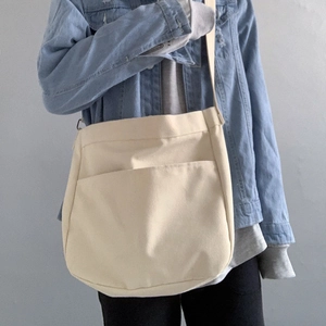 Detail of canvas crossbody bag showing large front pocket and metal strap adjuster