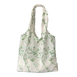 White semi-transparent mesh tote bag with green floral embroidery and minimalist design
