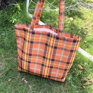 Vue détaillée du sac cabas en toile à carreaux orange montrant la texture et la sangle