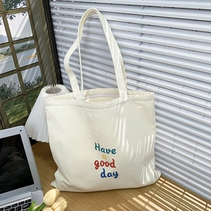 Detail of cream canvas tote bag featuring a colorful 'Have a good day' print design