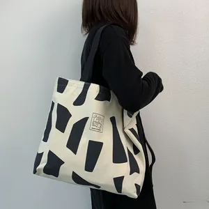 Detail of canvas tote bag with geometric print and Good Student patch on wide black strap