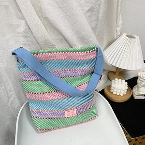 Detail der bunten gewebten Tasche mit rosa 'HAND MADE' Etikett und blauem Gurt