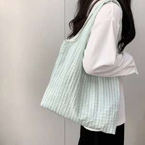 Detail of light green grid pattern tote bag with textured bubble fabric on a model