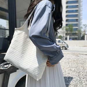 Close-up of white checkerboard canvas tote bag showing lightweight fabric and wide strap