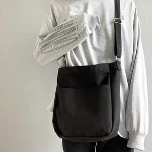 Detail of minimalist black canvas crossbody bag with adjustable strap and front pocket
