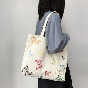 Detail of white canvas tote with colorful butterfly prints and woven happiness patch