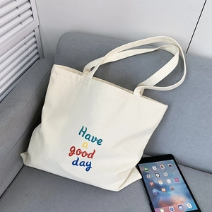 Detail of canvas tote bag with Have a good day print on a sofa beside a tablet