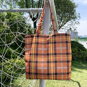 Détail du sac cabas à carreaux orange suspendu montrant la texture du tissu en toile tissée