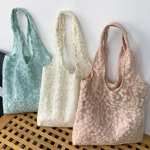 Floral embroidery canvas tote bags in green, cream, and pink on a wooden bench