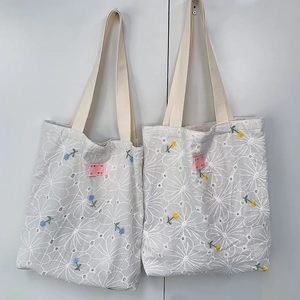 Detail of canvas tote bags with daisy hollow embroidery and hand made woven label