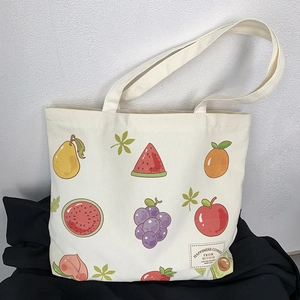 Detailed close-up of cream canvas tote bag featuring colorful cartoon fruit patterns